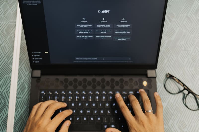Manos escribiendo en un portátil con ChatGPT abierto para buscar información con inteligencia artificial