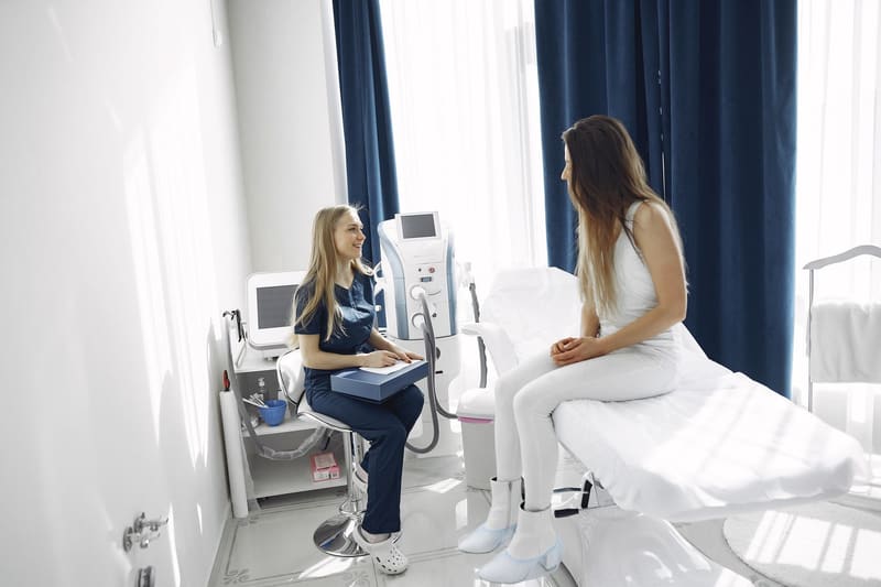 Profesional de una clínica de estética atendiendo a una paciente en la consulta