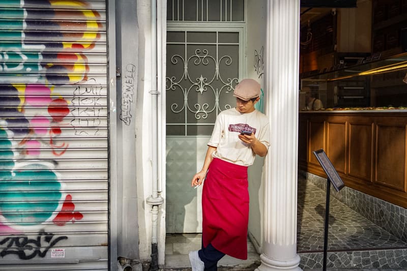 Dueño de un negocio local consultando las redes sociales en el móvil a la puerta de su local