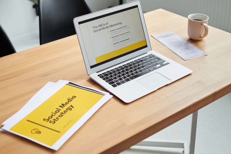 Portátil y documento de estrategia de redes sociales sobre una mesa de trabajo
