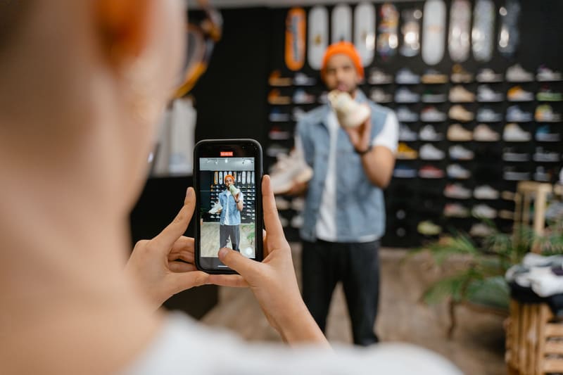 Persona grabando con el móvil un vídeo para redes sociales en una tienda de zapatillas